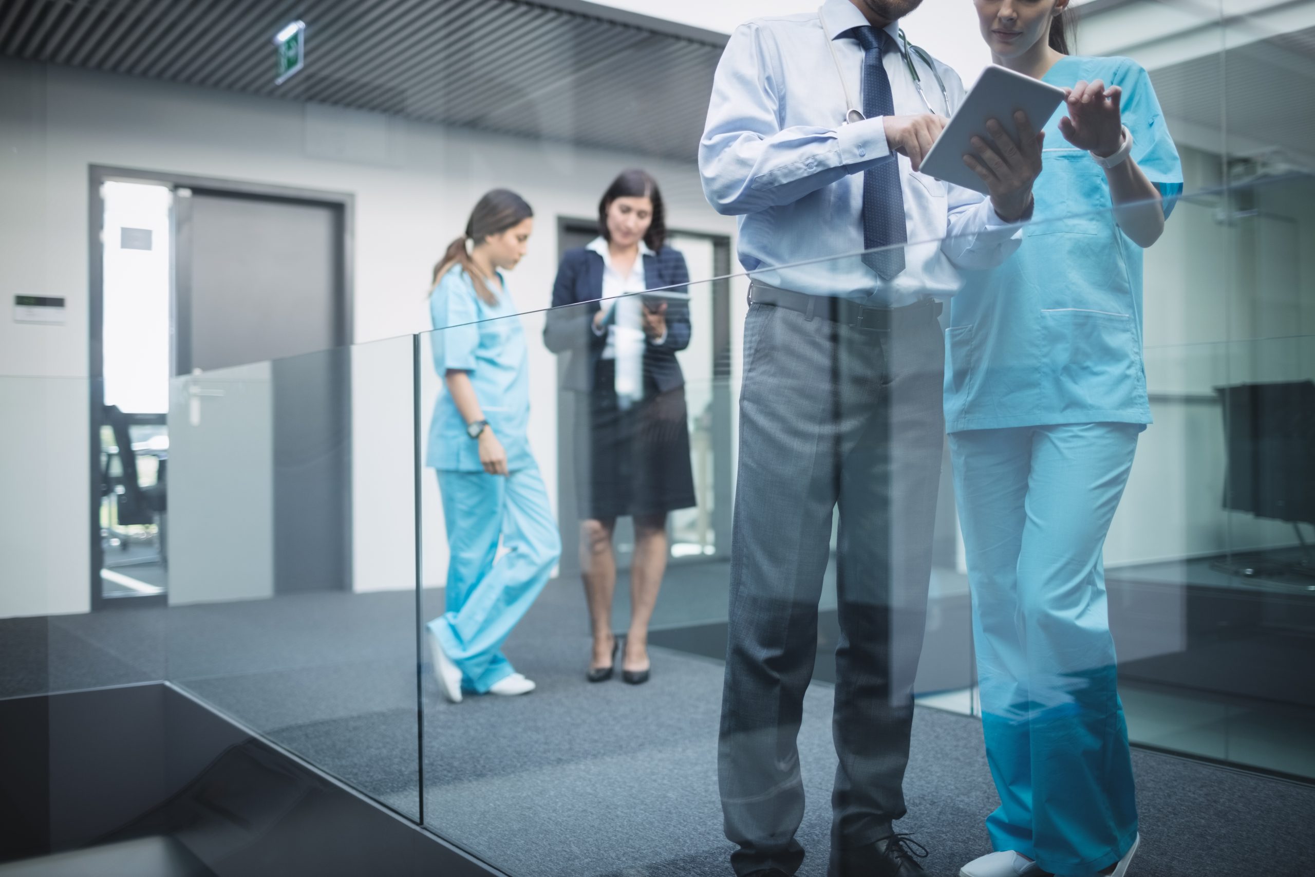 Doctors and nurses discussing over a digital tablet in a hospital corridor
