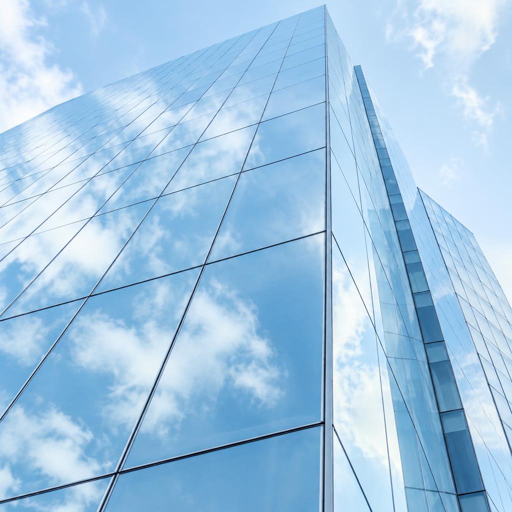 Glass office facade reflecting the sky
